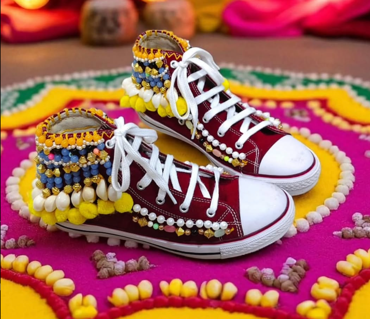 Maroon sneakers with white laces and colorful bead embellishments on a decorative mat.
